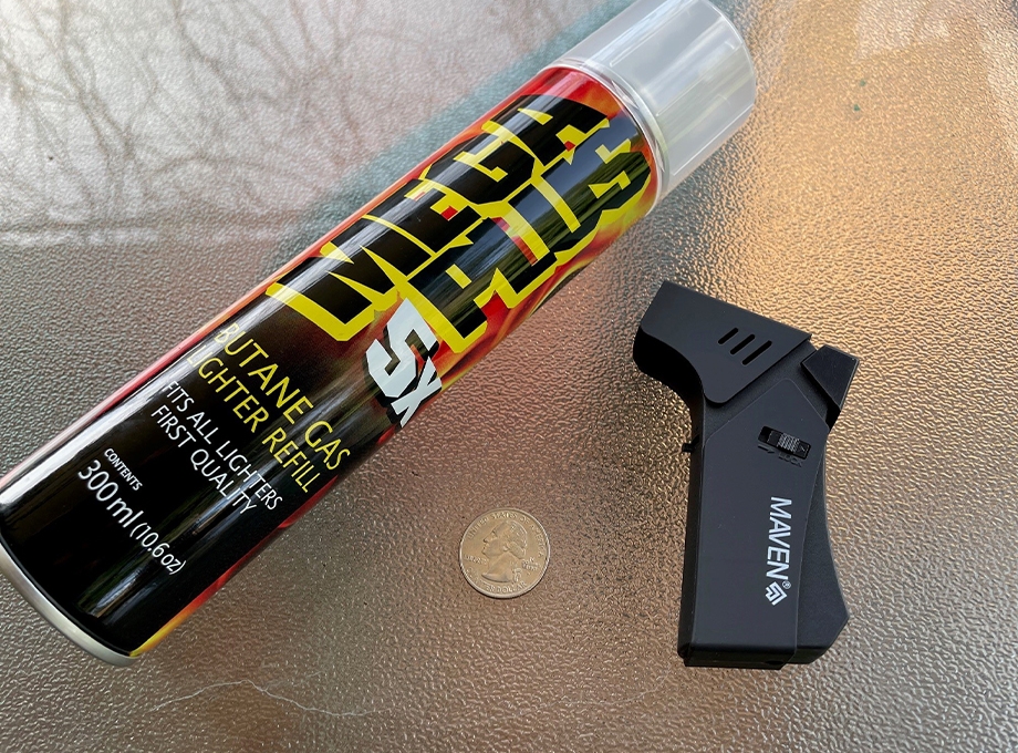 A butane torch and refill can are displayed on a table.